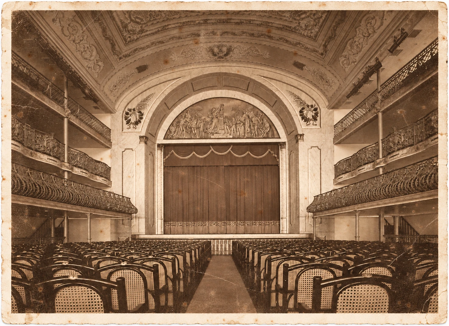 Fotografia de uma plateia vazia diante de um palco com cortina fechada e camarotes laterais, em sépia, com superfície envelhecida e borda branca desgastada.